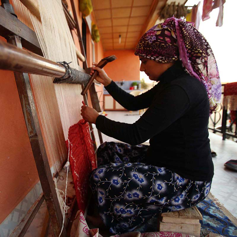 キリムを織り上げている女性の織り手の写真